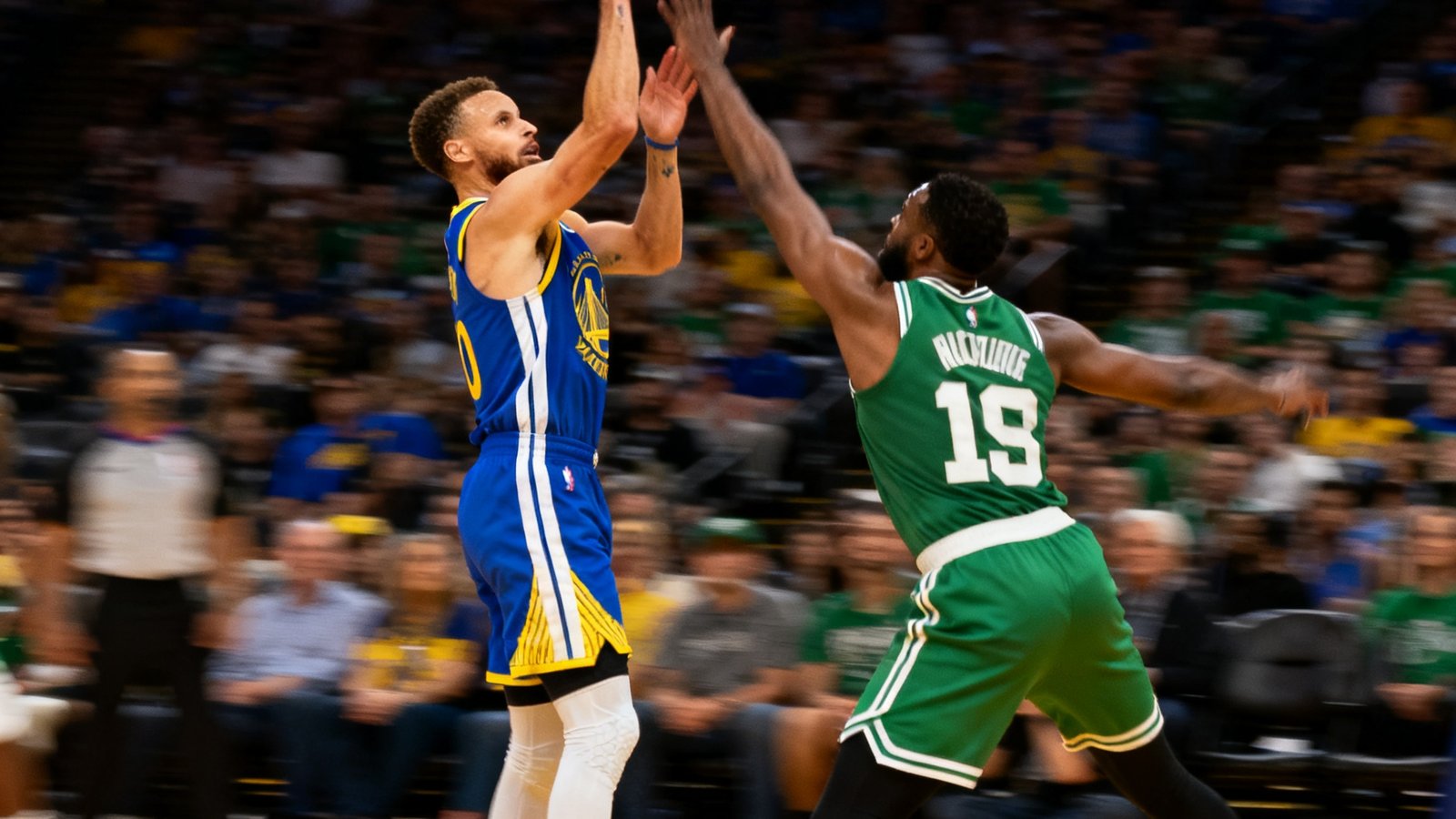 NBA比赛中勇士队与凯尔特人队激烈对抗的画面，库里在三分线外跳投出手的慢动作定格
